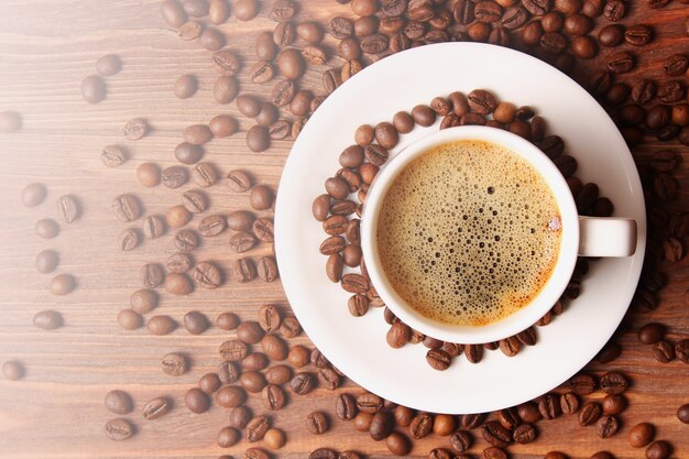 Cup of aromatic coffee and coffee beans on a wooden background