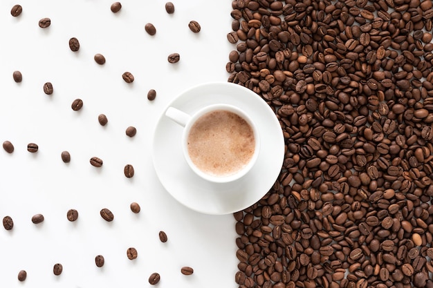 A cup of aromatic coffee and coffee grains on a white background top view