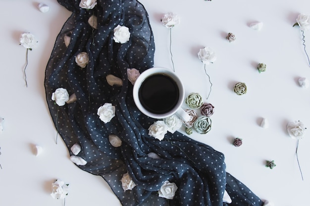 cup of aromatic hot coffee on deep blue fabric with flower decor. fall concept