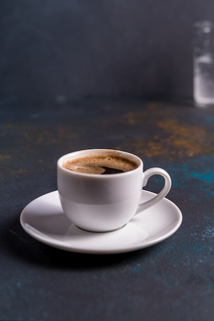 Cup of black coffee on blue table background