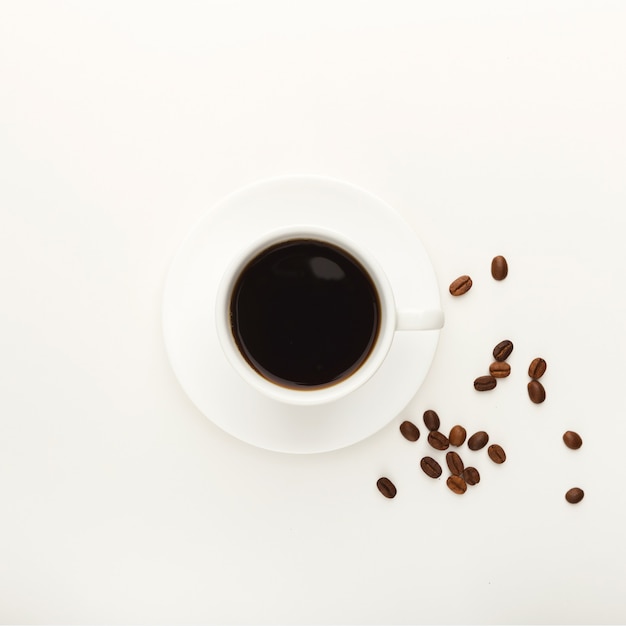 Cup of black coffee and roasted beans on white isolated background. Top view on bracing beverage. Mockup for adverticement design, copy space