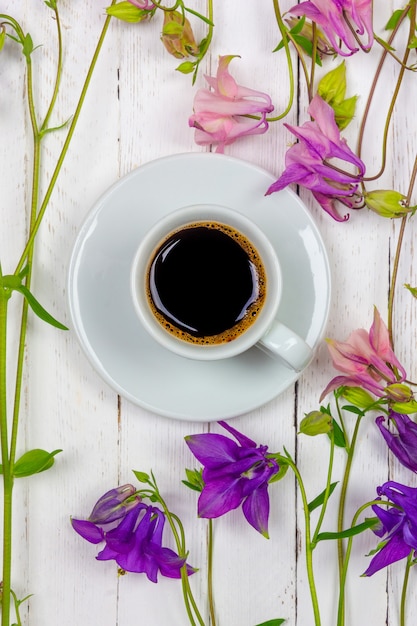 Cup of black coffee on a saucer among the flowers