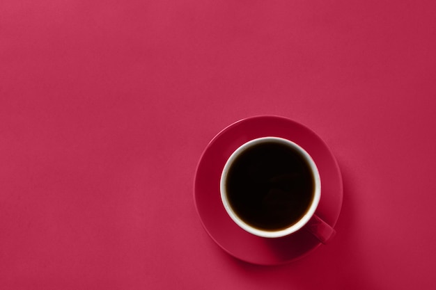 Cup of black coffee on viva magenta background