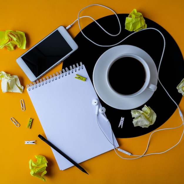 Cup of black coffee on vynil record. Notebook Copy space. Listening to music. Retro style. Podcast. Mobile phone with headphones.