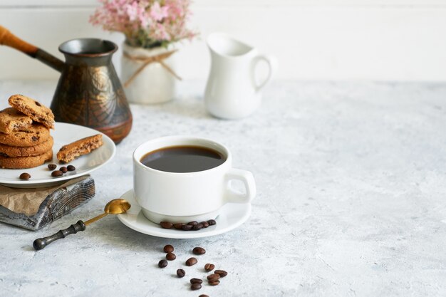 Cup of black strong coffee with coffee beans and cookies