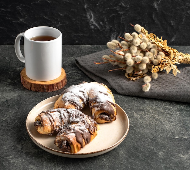 Cup of black tea traditional chocolate pastries willow on a dark background