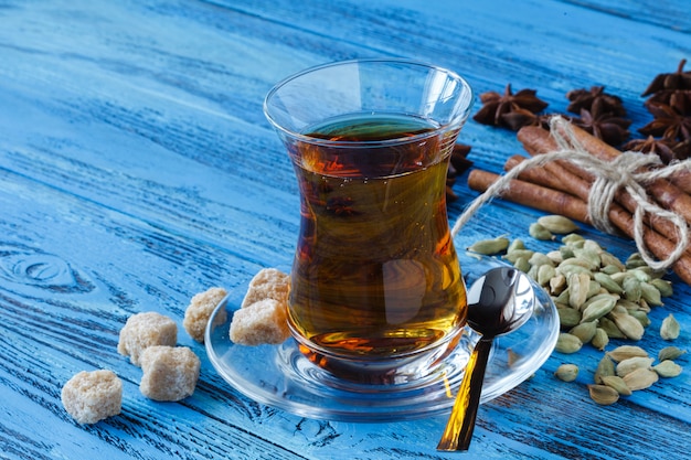 Photo cup of black tea on wooden table with cane sugar cubes