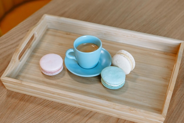 A cup of blue coffee standing on a wooden tray Macaroons are lying nearby