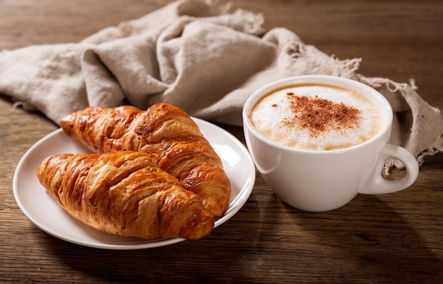 Cup of cappuccino coffee and croissants