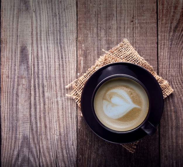 Cup of cappuccino coffee on old vintage wooden table