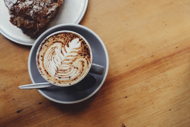 Cup of cappuccino coffee  with almond croissant