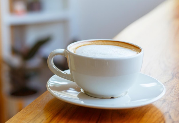 Cup of cappuccino coffee with a latte on a wooden bar in a sunlit cafe in the morning