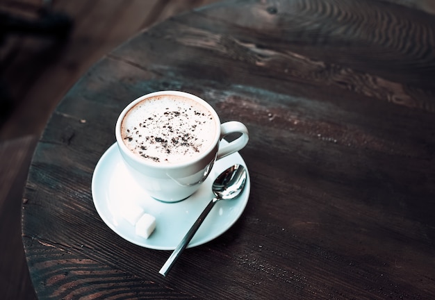 Cup of cappuccino on old dark wooden table