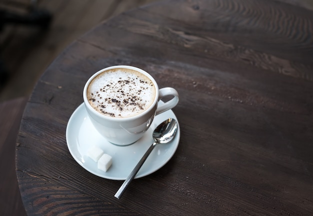 Cup of cappuccino on old dark wooden table