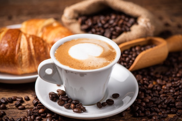 A cup of cappuccino with coffee bean as background close up