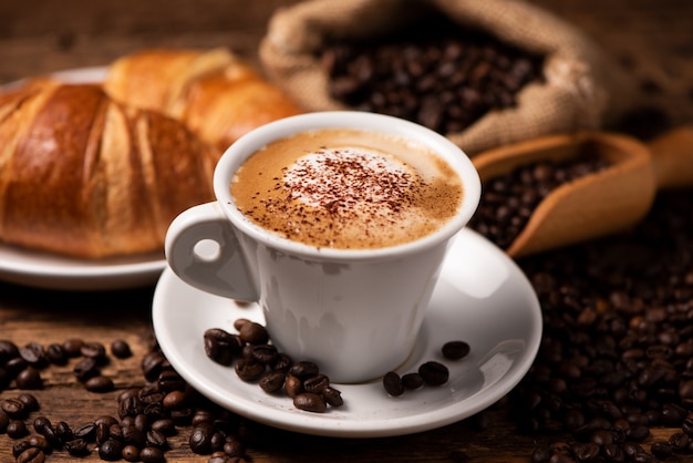 A cup of cappuccino with coffee bean as background close up