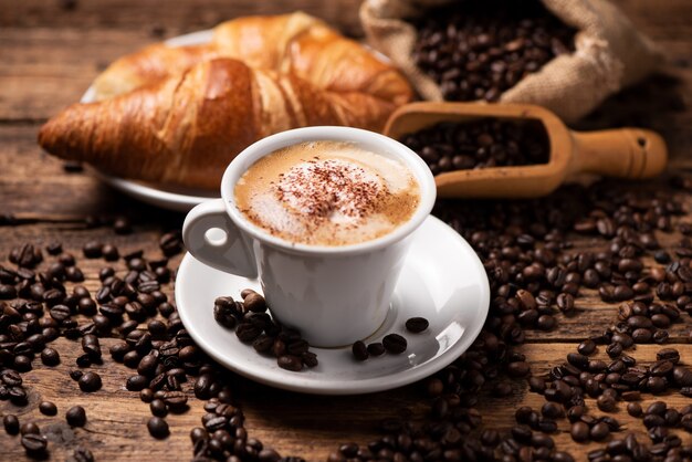 A cup of cappuccino with coffee bean as background close up