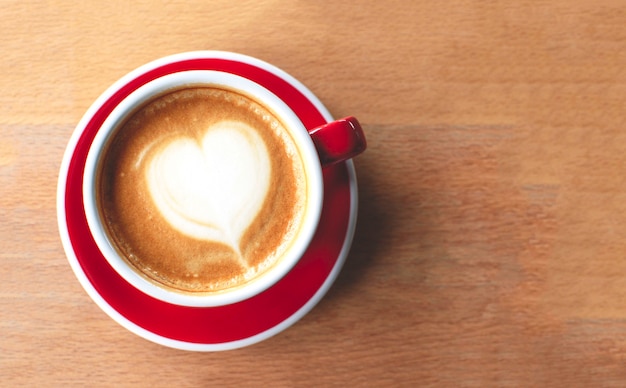 A cup of cappuccino with latte art on a wooden background.