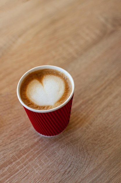 Cup of cappuccino with latte art on wooden table