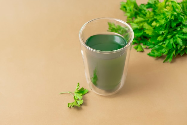 Cup of chlorophyll water on light beige background with copy space