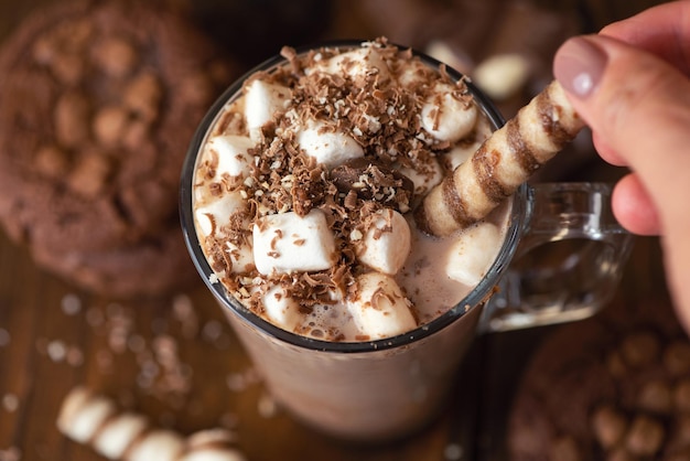 Cup of cocoa with marshmallows and chocolate chip cookies on dark wooden background Close Up