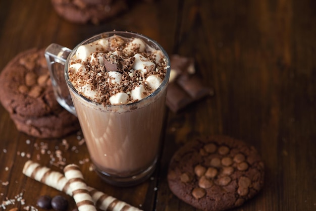 Cup of cocoa with marshmallows and chocolate chip cookies on dark wooden background