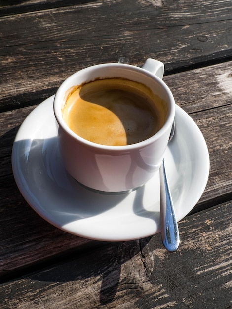 Cup of coffe image shape from shadow Yin Yang on wooden background White ceramic cup stylish toning copy space