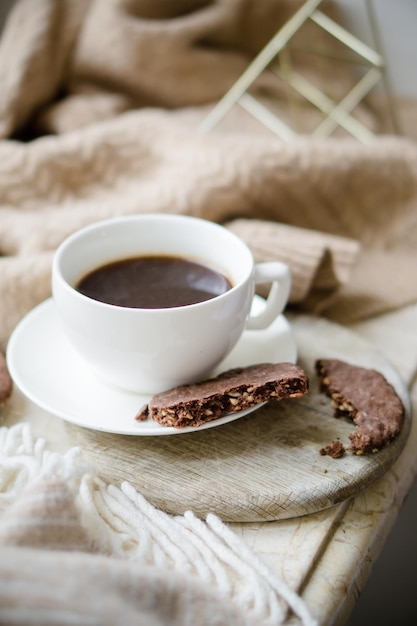 Cup of coffe with milk and chocolate cookies on warm wool blanket