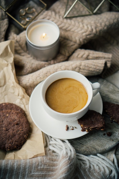 Cup of coffe with milk and chocolate cookies on warm wool blanket