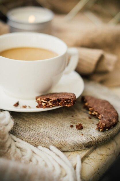 Cup of coffe with milk and chocolate cookies on warm wool blanket