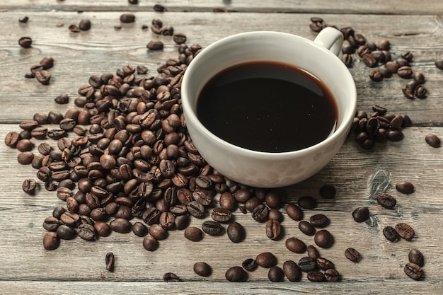 Cup of coffee and beans on wooden surface