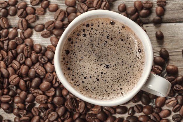 Cup of coffee and beans on wooden surface