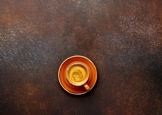 Cup of coffee on brown background with empty place for your text or lettering.