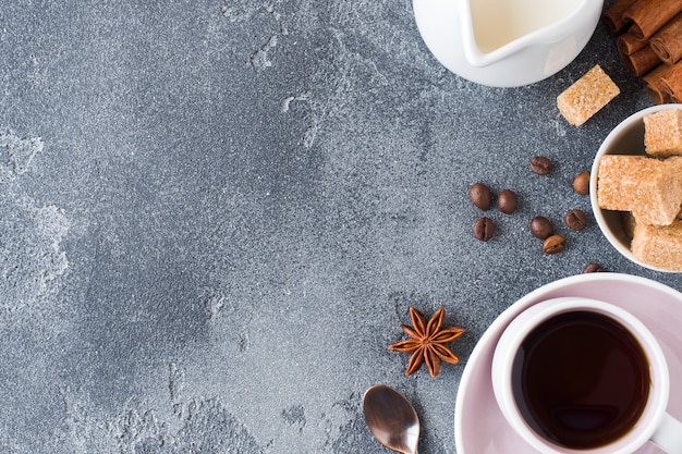 Cup of coffee, brown sugar and cinnamon with anise on concrete. Copy space