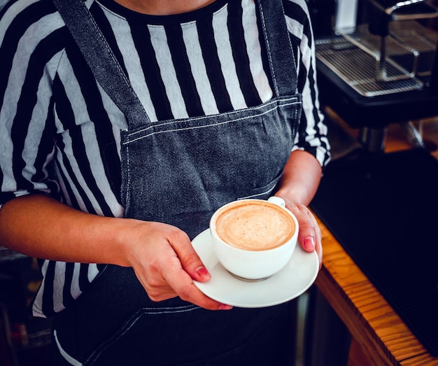 A cup of coffee cappuccino menu ready to serve in hand woman barista in the coffee shop