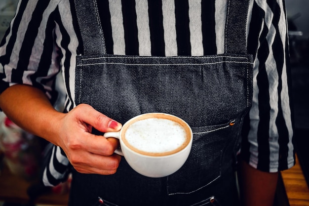 A cup of coffee cappuccino menu ready to serve in hand woman barista in the coffee shop