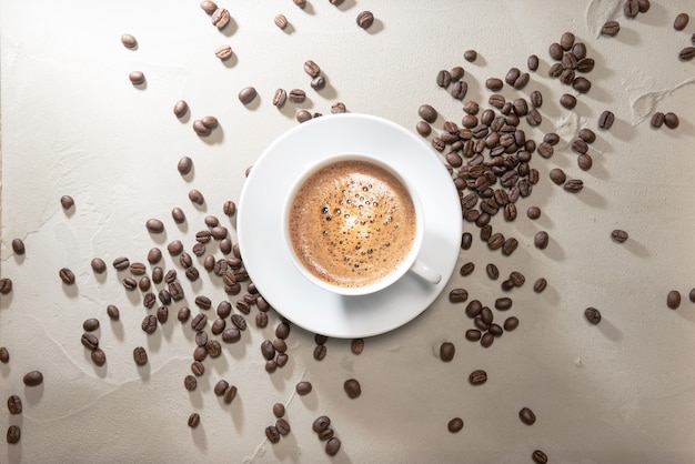 Cup of coffee cappuccino with coffee beans on a table vintage background