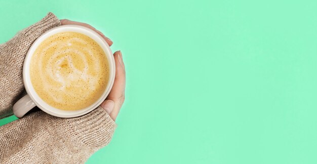 Cup of coffee cappuccino with milk foam in hands  