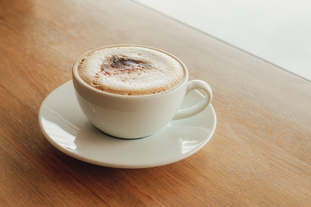 Cup of coffee cappuccino on wooden bar in cafe.