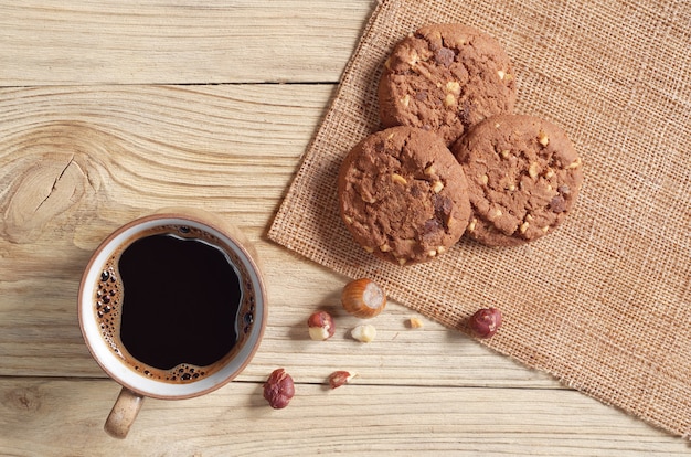 Cup of coffee and chocolate chip cookies with hazelnuts on the table