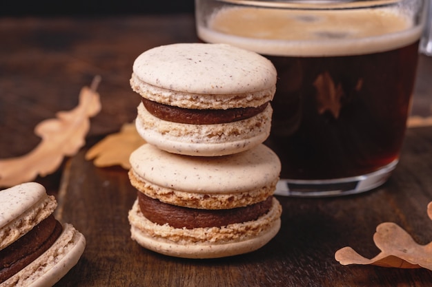 Cup of coffee and chocolate macarons on wooden background. Cozy autumn composition - Image