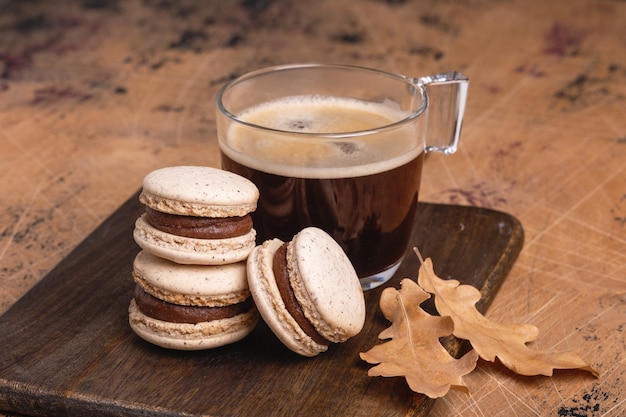 Cup of coffee and chocolate macarons on wooden background. Cozy autumn composition - Image