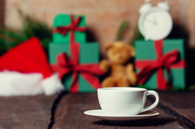 Cup of coffee and Christmas gifts on background on wooden table.