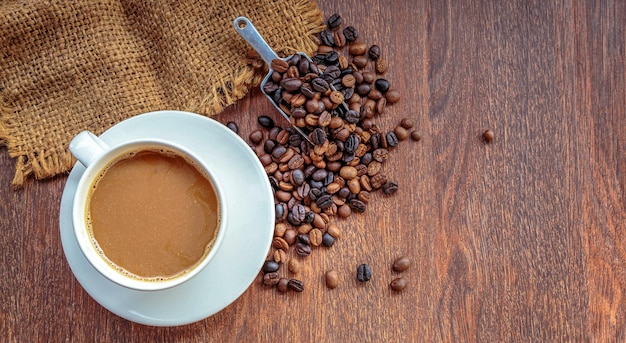 Cup of coffee and coffee beans in a sack on Brown background top view