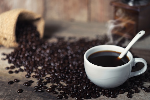 Cup of coffee and coffee beans on table