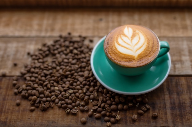 A cup of coffee and coffee beans on the wood table.