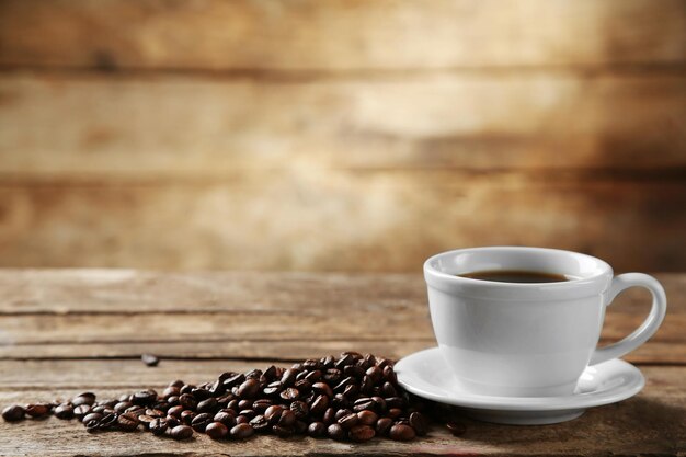 Cup of coffee and coffee grains on wooden background