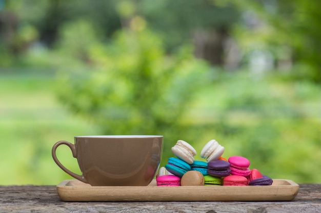 Cup of coffee and Colorful Macaroons in dish on wooden table