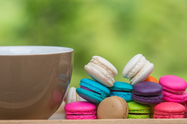 Cup of coffee and Colorful Macaroons in dish on wooden table