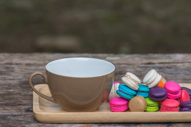 Cup of coffee and Colorful Macaroons in dish on wooden table